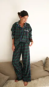 Conjunto de pijama a cuadros con ribetes en color lila, compuesto por camisa de manga larga con botones y pantalón largo.