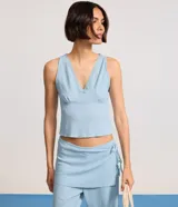 Blusa musculosa celeste confeccionada en anarruga, con escote en V y detalle de encaje.