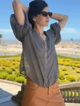 Camisa de gasa color gris con mangas abullonadas y detalle de piedras azules en el frente.