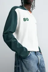 Camiseta de manga larga con cuello redondo, diseño color block en blanco y verde oscuro, con el número 80 y la inscripción 'Saint Frederic' bordados en el frente.