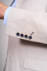 Saco sport color beige claro, de corte clásico, con solapa de muesca, dos botones frontales, bolsillos laterales con solapa y bolsillo en el pecho.