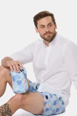 Short de baño celeste con estampado de hojas de palmera en tonos azules y rosados. Tiene cintura elástica con cordón ajustable, dos bolsillos laterales y suspensor de malla fina.