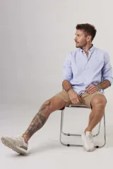 Camisa de hombre color crema, de corte clásico, con cuello abotonado y mangas largas.