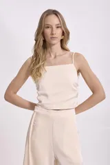 Crop top negro de satén con breteles finos regulables y corte holgado.