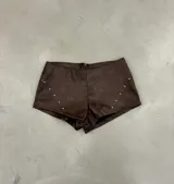 Short marrón de cuero sintético con tachas plateadas en los laterales.