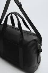 Bolso de viaje negro con acabado texturizado, compartimento principal con cierre de cremallera, bolsillo plano trasero con cierre de cremallera, banda de sujeción para equipaje y asa de hombro removible y ajustable.