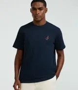 Remera de hombre color azul marino, corte regular, cuello redondo y manga corta. Presenta un pequeño bordado multicolor en el pecho que simula un barco y peces.