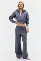 Pantalón de jogging gris de corte holgado, con cintura elástica ajustable con cordón, bolsillos laterales y piernas anchas.