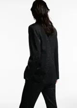 Blazer negro con pequeños apliques brillantes, cuello con solapa, cierre con un botón, dos bolsillos delanteros con solapa, forro interior y corte recto.