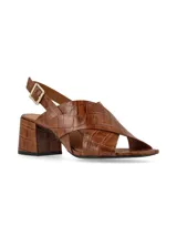 Sandalias negras de charol con tiras cruzadas, tacón cuadrado y pulsera al tobillo con hebilla metálica.