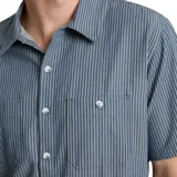 Camisa de manga corta a rayas verticales color azul con cuello clásico, cierre frontal con botones y dos bolsillos de parche en el pecho. Corte recto.
