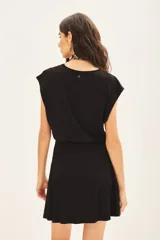 Vestido corto negro de morley con cuello redondo, elástico en la cintura y falda con capas. Incluye medallita marcaria en la espalda.