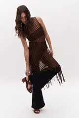 Sandalias de cuero color beige, con dos tiras horizontales sobre el empeine, una con apliques de tachas y otra con calados. Tienen pulsera con hebilla al tobillo y taco cuadrado de madera.