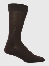 Calcetín de vestir largo, color marrón oscuro, con tejido fino y elástico acanalado en la caña. Presenta el logo de Hush Puppies grabado sutilmente en la parte inferior de la caña.