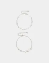 Set de dos pulseras plateadas con cierre de mosquetón y cadena de alargue. Una pulsera es de cadena de eslabones rectangulares y la otra es de cadena fina con dijes de corazones calados.