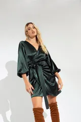 Vestido corto color fucsia de satén, con escote cruzado, mangas largas abullonadas y falda cruzada con lazo en la cintura.