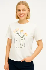 Remera blanca de algodón con estampado de flores en un jarrón.
