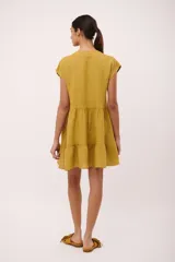 Vestido corto de lino color vino tinto, con escote en V y mangas cortas tipo musculosa. Presenta un corte holgado con volados en el ruedo.