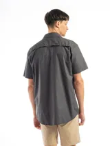 Camisa de manga corta color beige con cuello clásico, cierre frontal con botones, dos bolsillos con solapa abotonada en el pecho y corte recto. Ideal para actividades al aire libre.