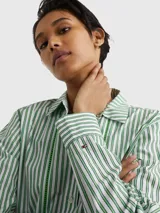 Camisa de corte amplio, a rayas verticales verdes y blancas, con cuello inglés, cierre frontal con botones y logo de Tommy Hilfiger bordado en el puño.