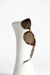 Lentes de sol estilo ojo de gato, montura negra brillante y lentes oscuros polarizados.