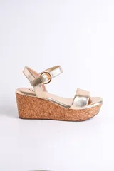 Sandalia dorada con plataforma de corcho, diseño cruzado y pulsera con hebilla.