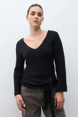 Sweater de tejido de punto negro, con escote en V pronunciado y mangas largas acampanadas. Presenta un lazo ancho anudado a la cintura.
