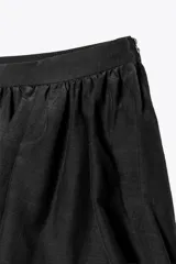 Falda pantalón corta negra de tiro medio, con cintura elastizada y detalle de tejido con volumen y pliegues. Cierre lateral con cremallera oculta.