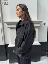 Campera clásica de jean negra con cuello camisero, bolsillos frontales y detalles de brillos plateados.