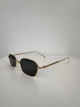 Lentes de sol con armazón metálico dorado y lentes rectangulares color negro.