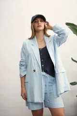 Blazer celeste de lino con solapas de muesca, cierre cruzado con botones, bolsillos delanteros con solapa y corte holgado.