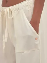 Pantalón estilo cargo color crudo, confeccionado en lino tencel. Cuenta con bolsillos laterales, elástico en la cintura y detalle de Polonio en cobre.