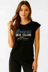 Remera color crema de algodón con estampado de un velero y la frase "Rough Waters Make The Best Sailors" en azul.