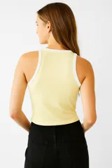 Musculosa amarilla de algodón con breteles anchos con borde blanco y bordado de flores en el pecho.