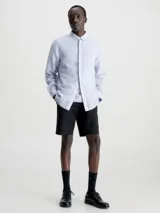 Camisa celeste de lino y algodón, de corte regular, manga larga, cuello en punta, cierre de botones oculto y bolsillo de parche en el pecho con monograma de Calvin Klein en la misma gama de tonos.