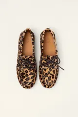 Mocasín tipo boat shoe con estampado de vaca en tonos marrón y blanco, confeccionado en cuero. Cuenta con cordones de cuero marrón oscuro y suela de goma.