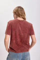 Remera color terracota con cuello redondo y estrellas bordadas alrededor del cuello.