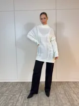 Sweater largo blanco de acrílico con cuello alto y diseño trenzado.