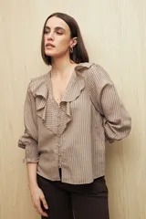 Camisa blanca a rayas verticales, con escote en V, mangas 3/4 con puños elastizados y volados.