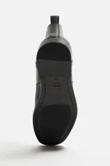 Bota Chelsea de cuero negro, con elásticos laterales, tirador trasero y suela con ligero tacón.