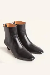 Bota corta de cuero vacuno con estampado animal print serpiente en tonos blanco y negro, con puntera fina y cierre trasero. Tiene taco chupete y suela de cuero.