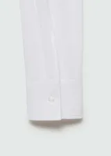 Camisa blanca entallada de popelina de algodón con cuello camisero, cierre frontal con botones y mangas largas con puños abotonados.