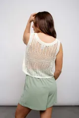 Blusa de tejido de punto calado color crema, sin mangas y corte crop.