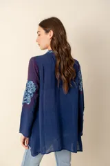 Túnica azul con bordados florales, cuello camisero y botones forrados.