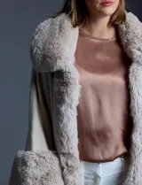 Ruana tejida color crema de la marca Adrienne Vittadini, con cuello, delantera y puños con aplique en símil piel. Delantera con abertura central y botón trenca.