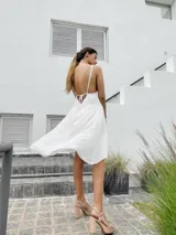 Vestido corto color naranja, con escote halter y diseño asimétrico con capas. Espalda con tiras regulables.