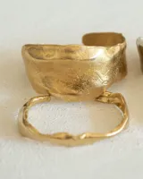 Brazalete rígido plateado con textura irregular.