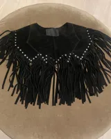 Chaleco negro de cuero vacuno con flecos y tachas plateadas.