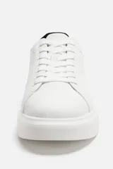 Zapatillas urbanas de cuero sintético negro con cordones y suela blanca de goma con volumen.