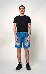 Bermuda de denim azul con efecto desgastado y roturas en ambas piernas. Presenta bordes deshilachados y un forro estampado visible en las aberturas. Tiene cierre frontal con botón metálico y cinco bolsillos.